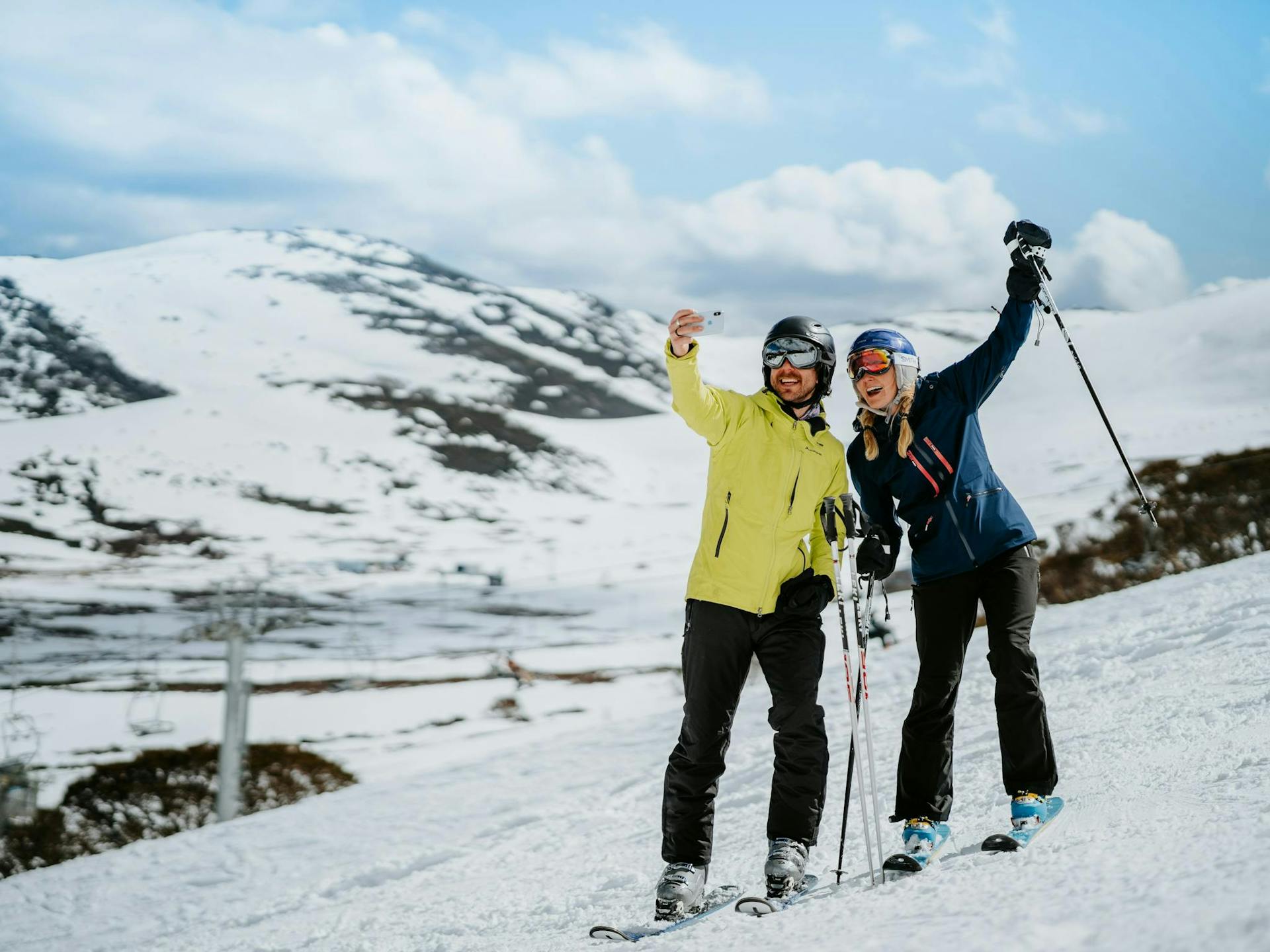 Skier couple in colorful ski attire taking a selfie on the slopes of Falls Creek in Australia.