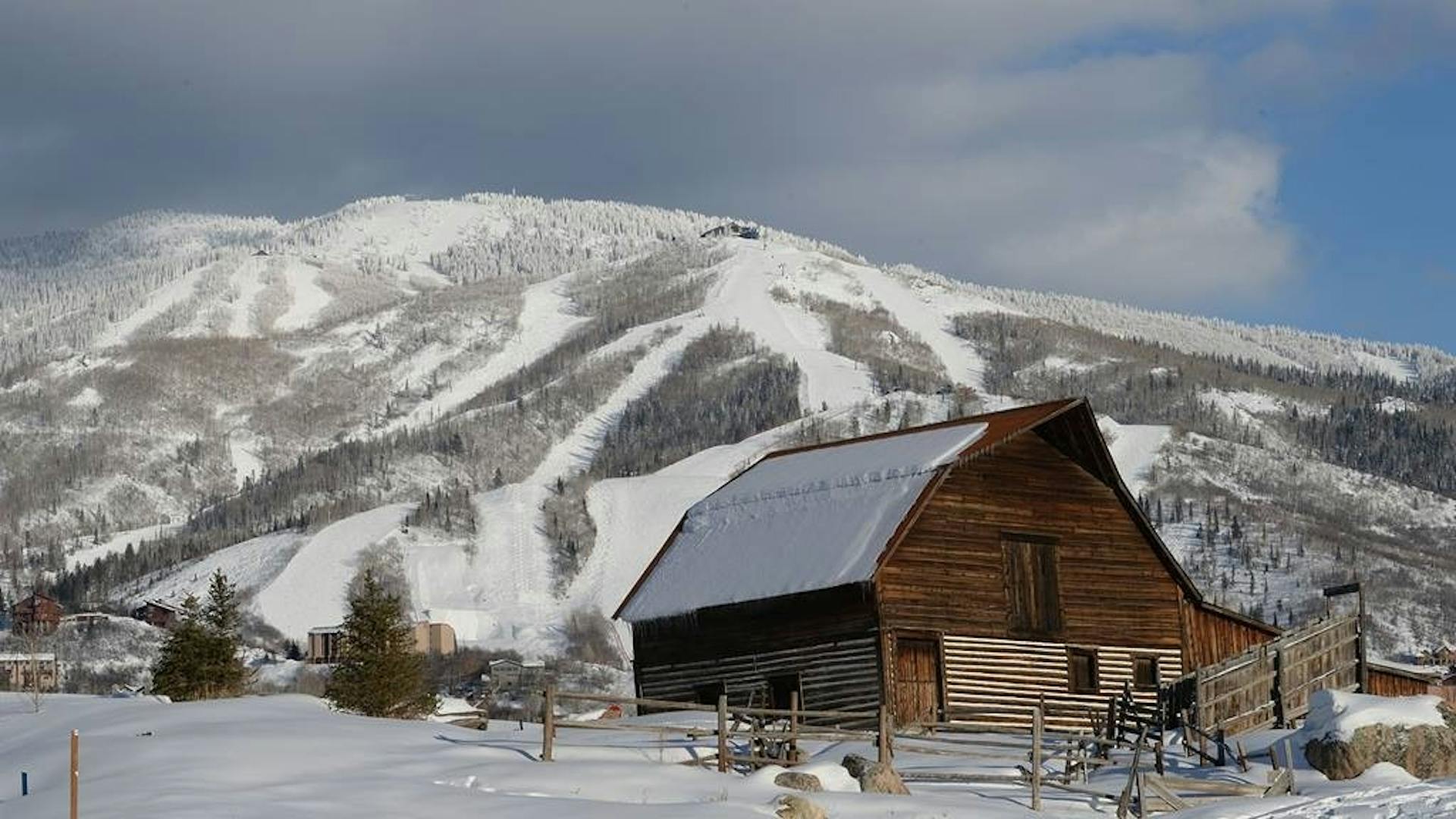Snow-covered barn in front of the snowy slopes of Steamboat Springs in Colorado, USA.
