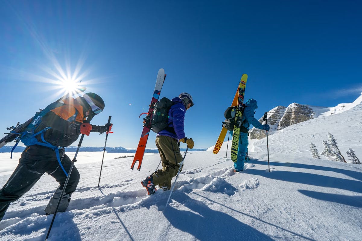 Three skiers of undiscernible gender in coloreful ski attire hitting the slopes at Jackson Hole in Wyoming, USA.