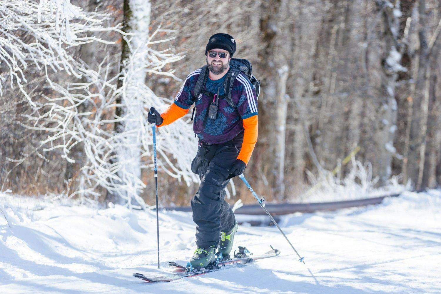 Male skier in orange and blue ski attire hitting the slopes at Jiminy Peak in Massachusetts, USA.