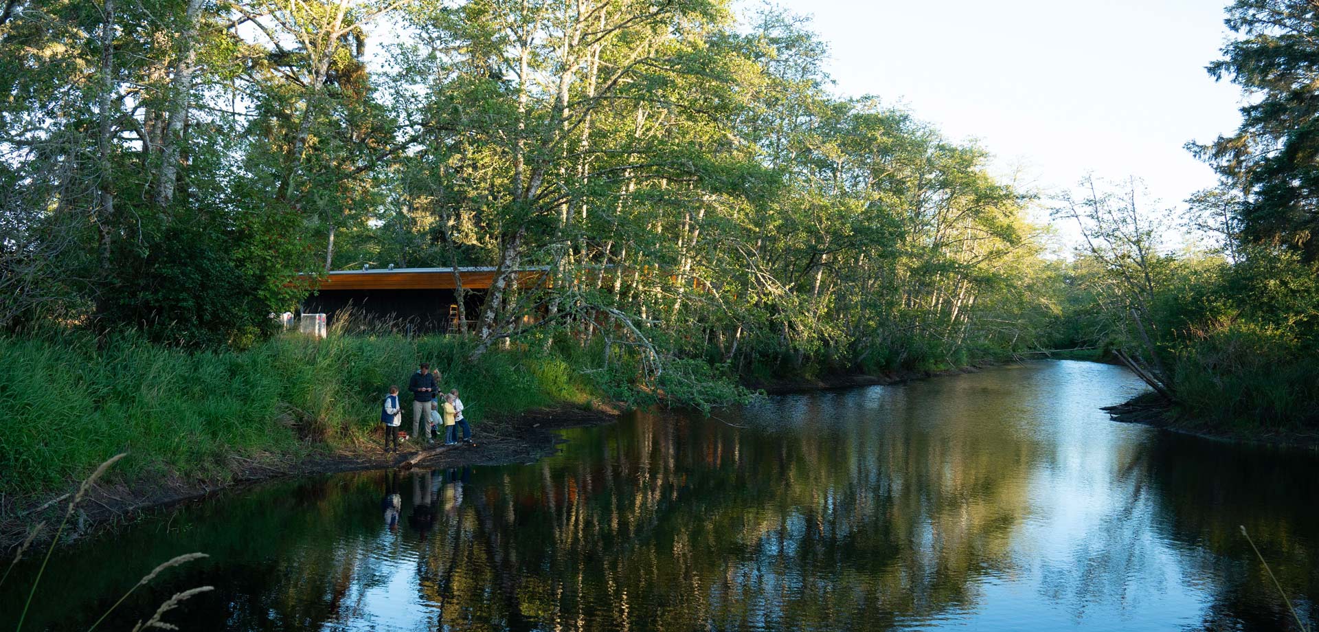 a photo of a pond and an adult and three children by it