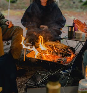 a close up of a fire pit with people around it