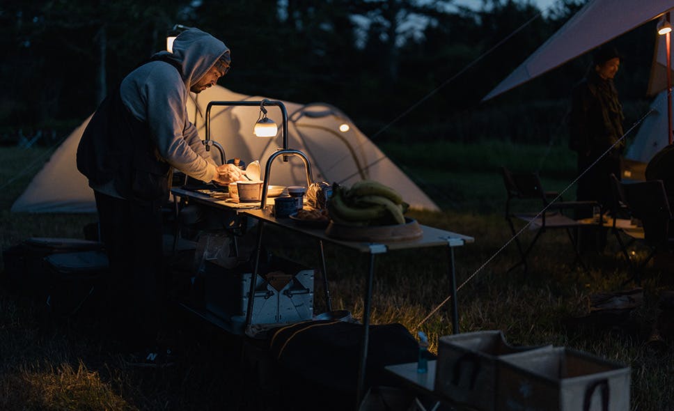 a photo of someone preparing food at night in a campsite