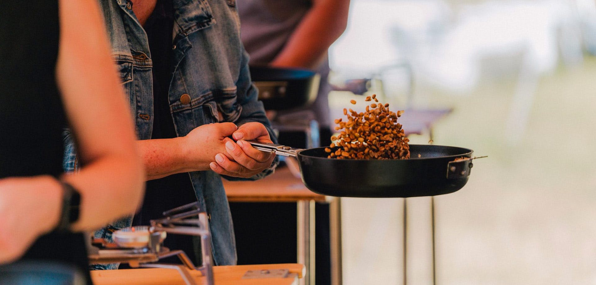 a close up of someone tossing coffee beans in a pan