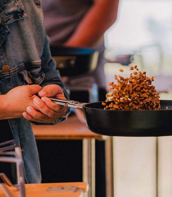a close up of someone tossing coffee beans in a pan