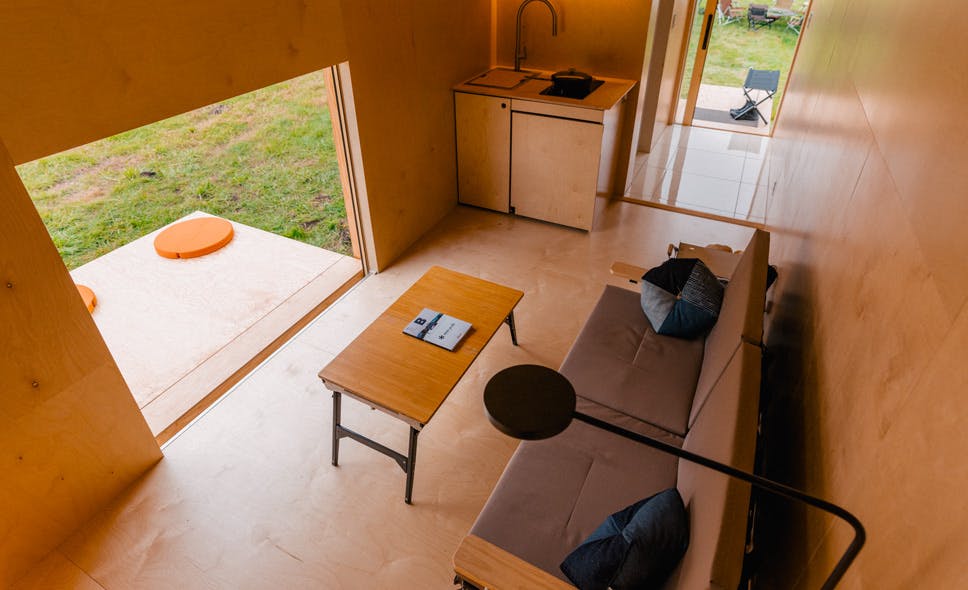 interior wide angle photo showing wooden walls, a couch and windows