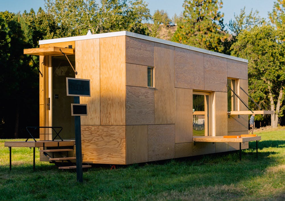 A photo of a Snow Peak Jyubako which is a cabin with raw plywood siding.