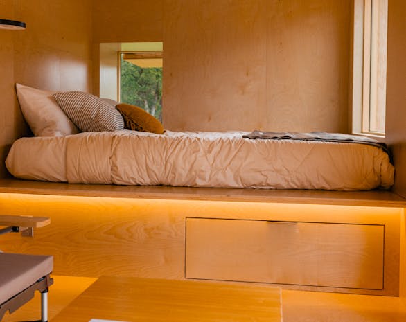 a photo of a warmly lit room with a bed and wooden walls