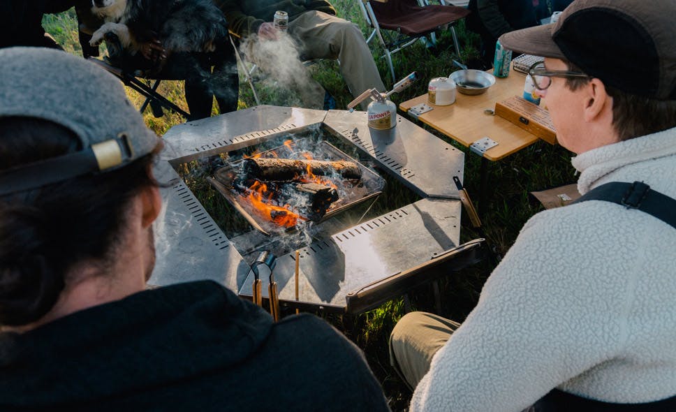a photo of a group around a fire and table