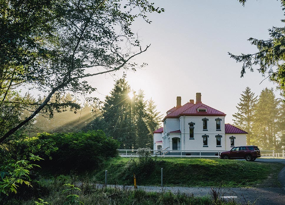 a photo of an old residential building exterior with a red roof and surrounding trees with beams of light