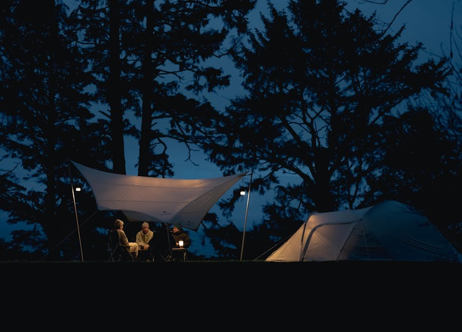 A photo of an ivory tent and tarp lit up at night time
