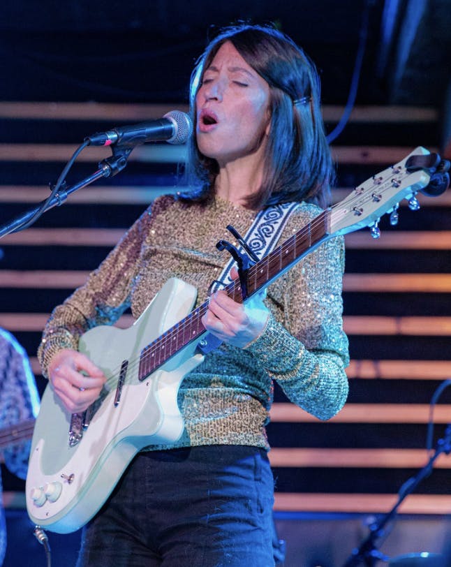 Debbie Miller singing on stage playing a guitar