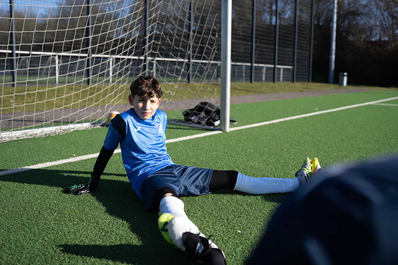 Goalkeeper sliding to block ball during save attempt on pitch - PWR PLY Soccer Academy