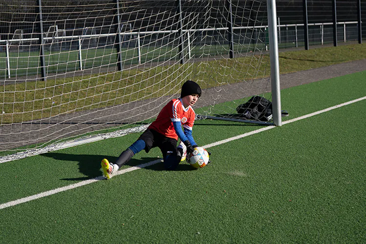 Torwart fängt den Ball am Boden während einer Trainingsübung – PWR PLY Soccer Academy