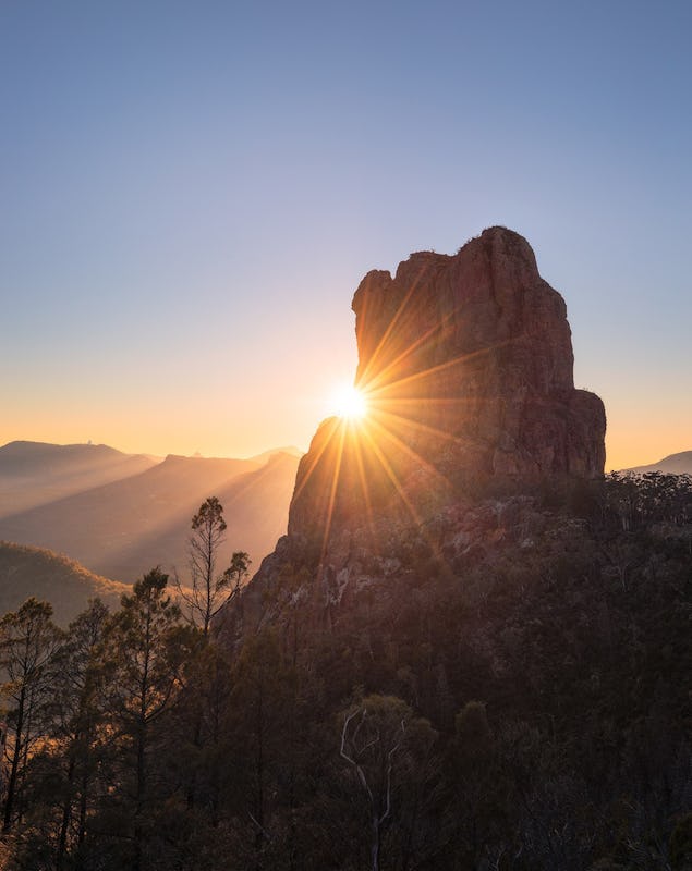 Sun rising over the Breadknife rock formation in Warrumbungle National Park.