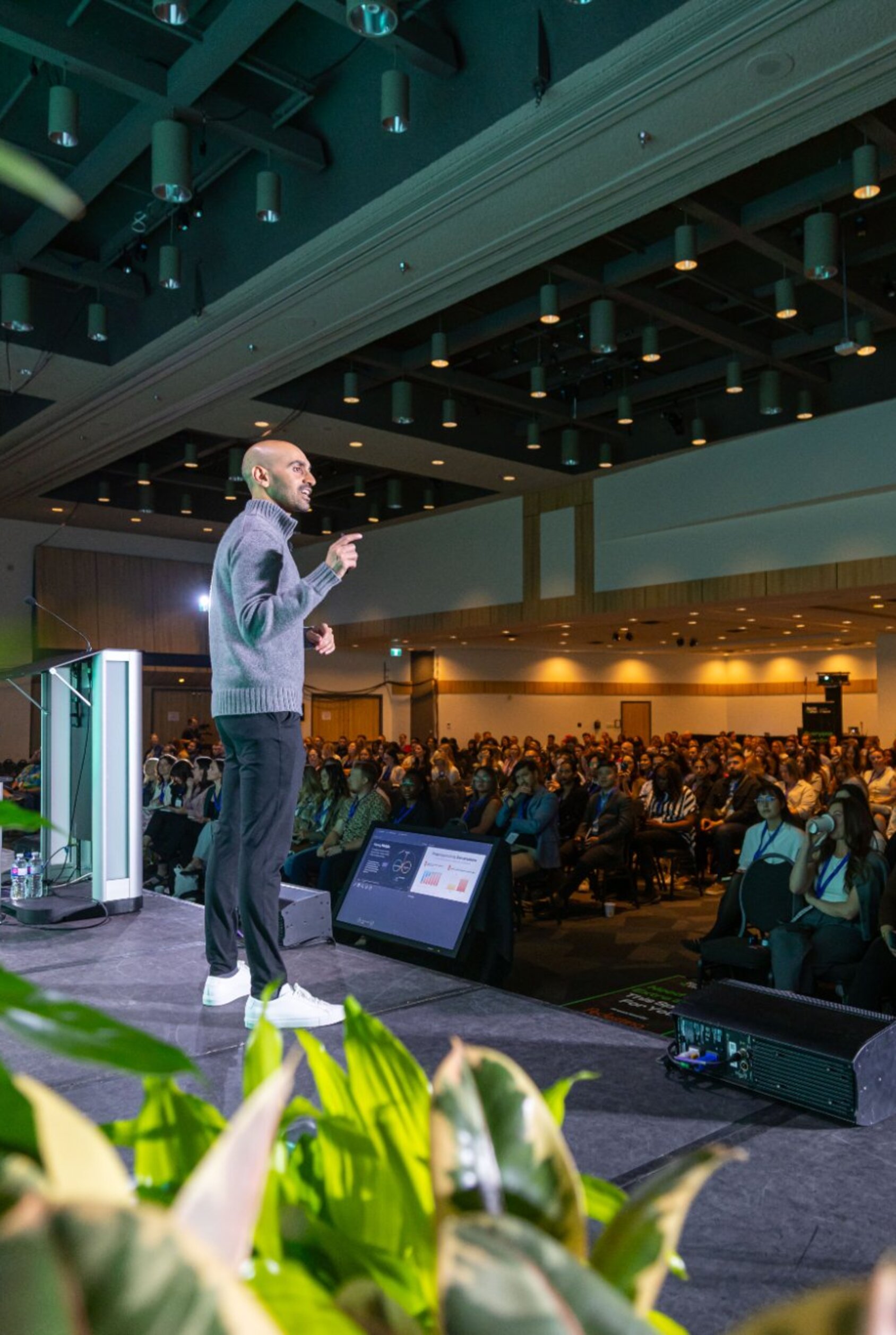 A keynote speaker addresses a packed conference hall at SocialWest, with hundreds of attendees seated in front of the main stage at the TELUS Convention Centre.