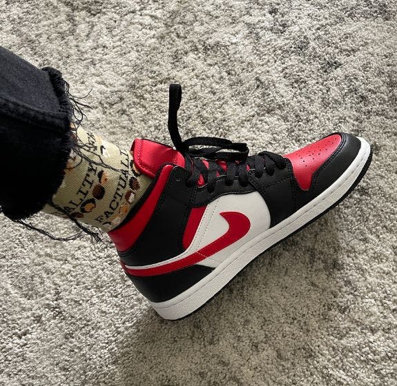 Custom sock for FACTUALITY the game being worn with a pair of black, white, and red Nike shoes