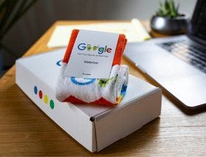 A corporate gift box from Google with a pair of branded socks sitting on a desk in a modern office