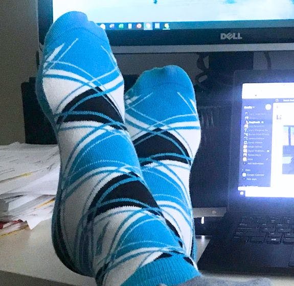 Custom argyle socks for Acuity being worn by a remote employee with his feet up on his desk