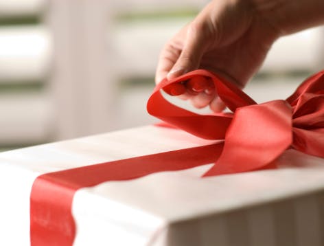 Present packaged in white wrapping paper with red ribbon