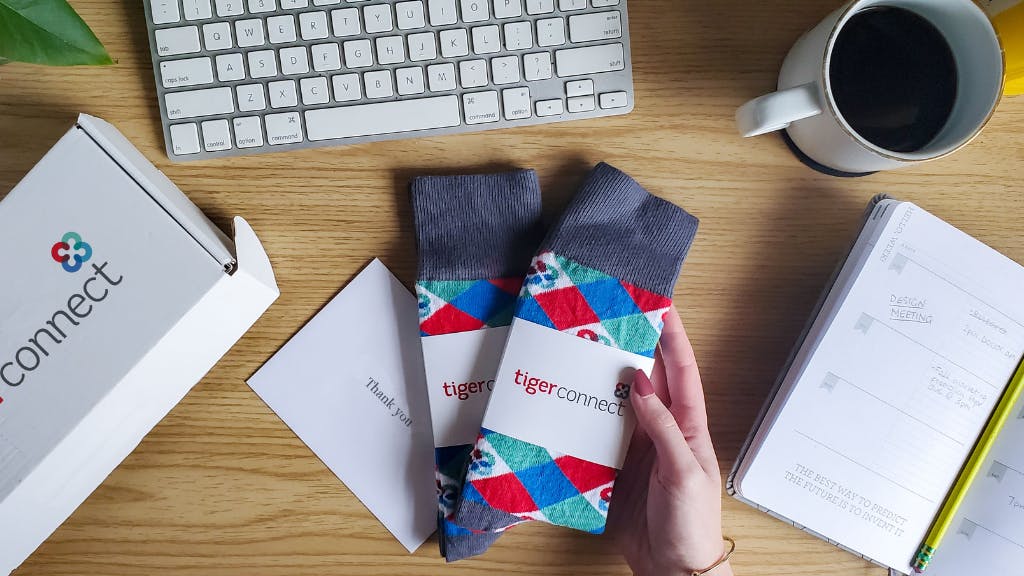Two pairs of custom branded socks on desk with work materials and custom gift box.