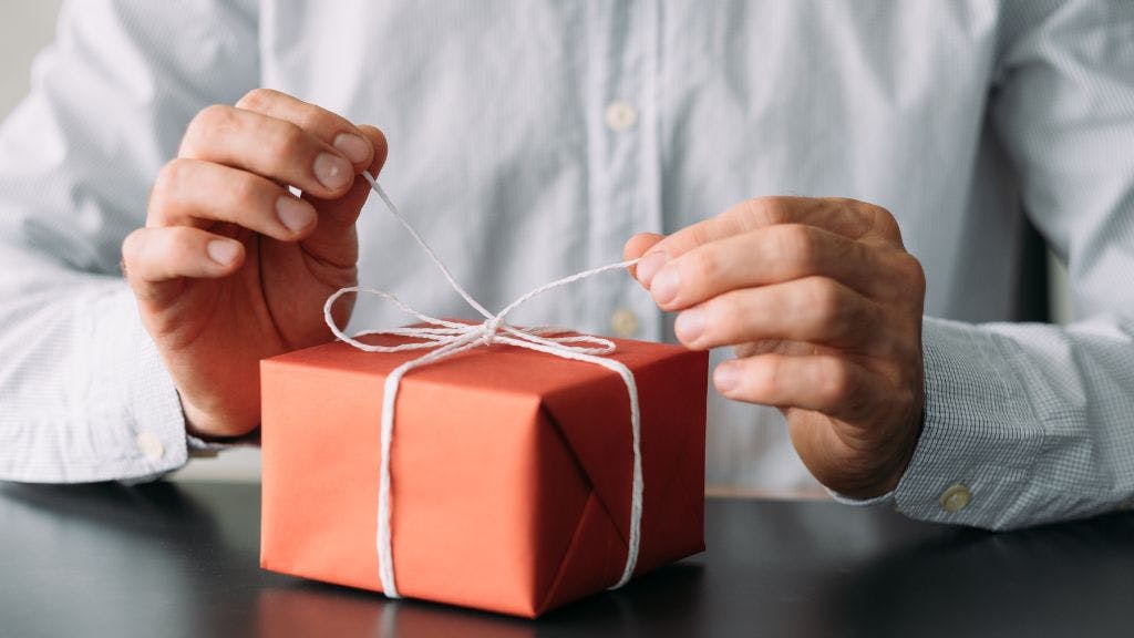 Business person opening a corporate gift that was sent to him to generate his business