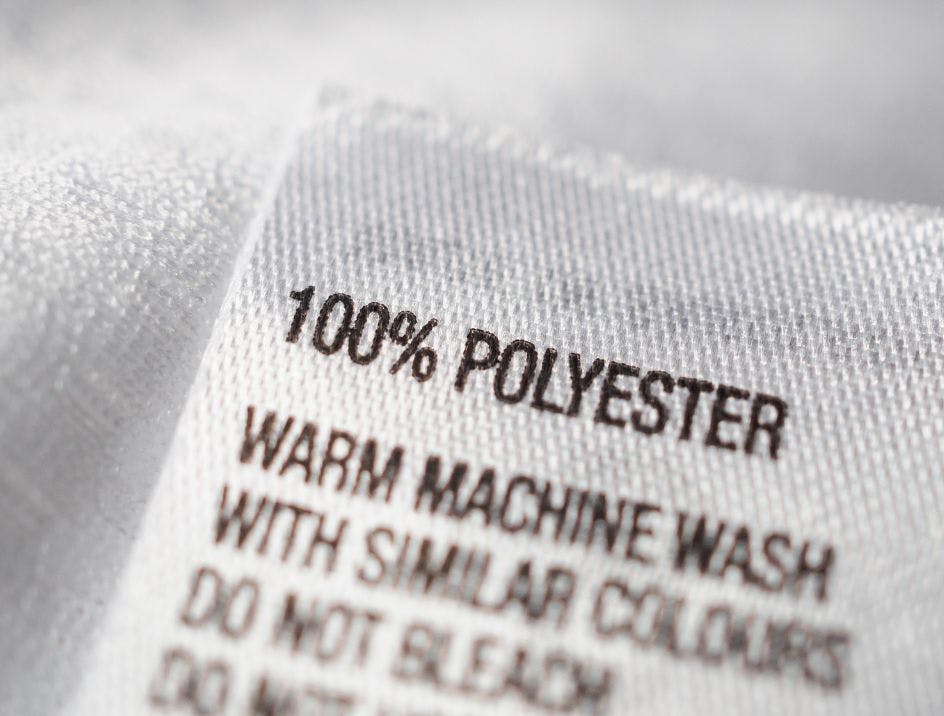 White label on a garment showing that it is made of 100% polyester and detailing the care instructions for the fabric