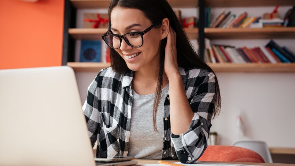 Engaged employee working from her home office and smiling at a laptop looking at customization options on her company swag store