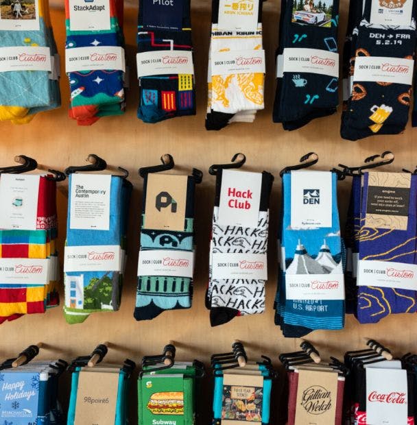 Merchandising display showing a number of custom socks designed for corporate merchandise hanging on the wall