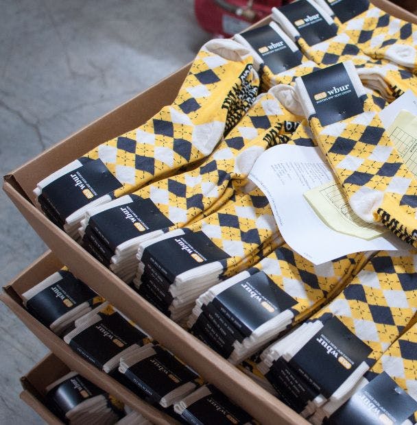 Bulk Customizable Socks for WBUR radio station in Boston with a yellow and black argyle pattern in a box at the sock manufacturing mill