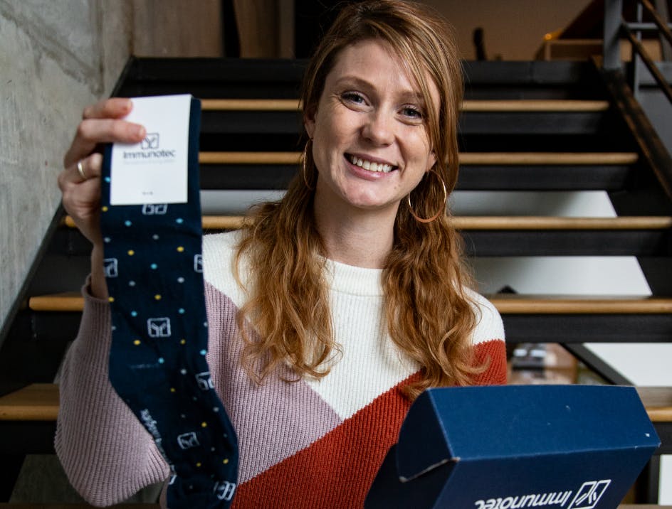 Person holding blue custom logo socks and custom box while smiling
