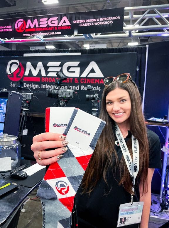 Omega Broadcasting holding up the custom socks that they used as trade show giveaways