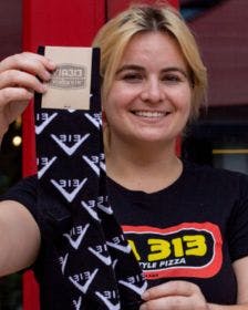 A Via313 employee holding up the branded socks that they made for restaurant merch