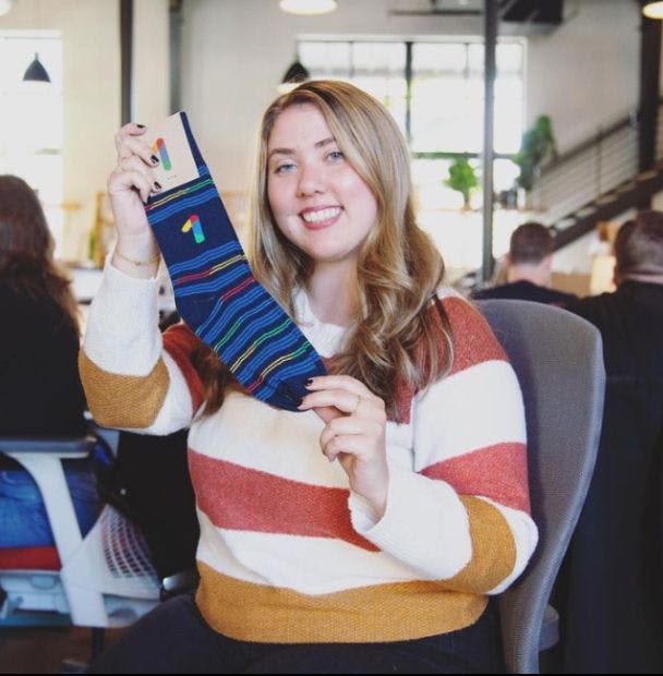 Happy employee holding up a branded sock that she got as an employee appreciation gift
