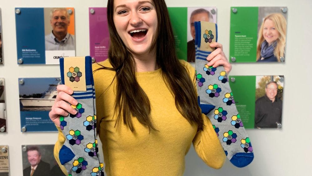 NEXDINE team member holding up a pair of branded socks that she got as an employee appreciation gift