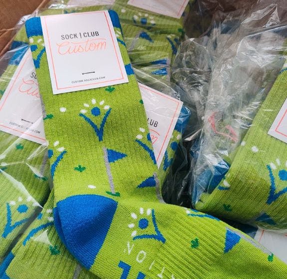 Custom branded socks for the donors of the Elevate Foundation featuring their green and blue branding