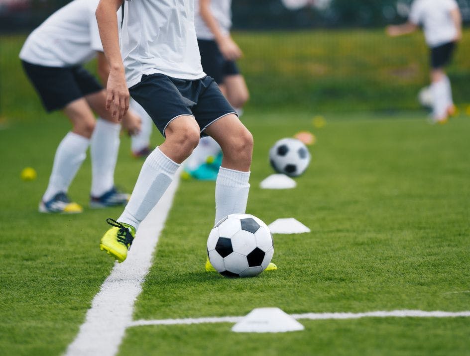 Soccer player with white knee socks for soccer kicking the ball on the field in practice