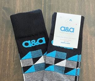 Custom socks for A&A Elevated Facility Solutions that have a striped pattern on them in blue and white with the company logo