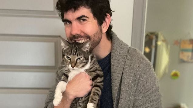 Sales Operations Manager Ryan Wood holding his pet cat and smiling