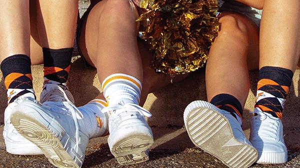 People wearing orange and black custom football socks for UT Austin