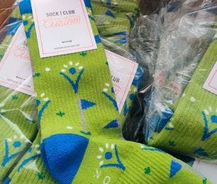 Custom branded socks for the donors of the Elevate Foundation featuring their green and blue branding