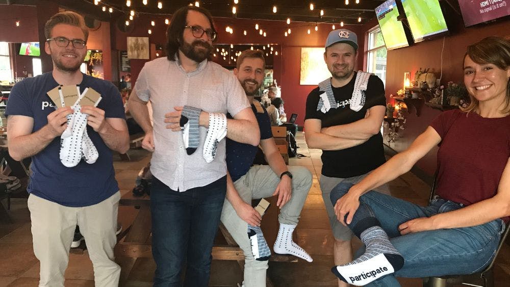 The Participate team at their quarterly meeting showing of the branded socks from Sock Club that they received from Sock Club as employee appreciation swag