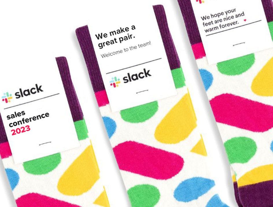 Three branded socks for Slack with different messaging on the custom sock header cards, including "we make a great pair" and "we hope your feet are nice and warm forever."