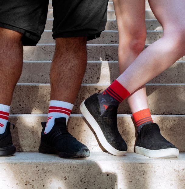 custom golf socks being worn by two young people on stairs with sneakers on 