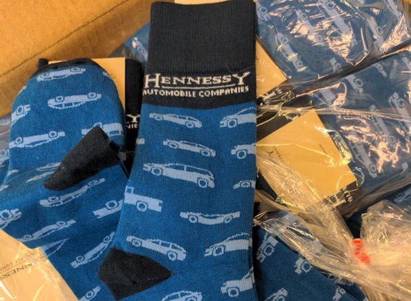 Blue custom logo socks for Hennessy Auto with car icons repeating 