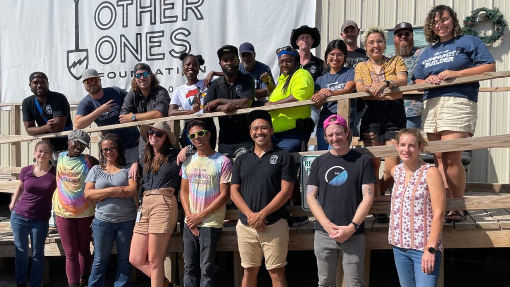 Smiling group of people standing in front of a large white banner.