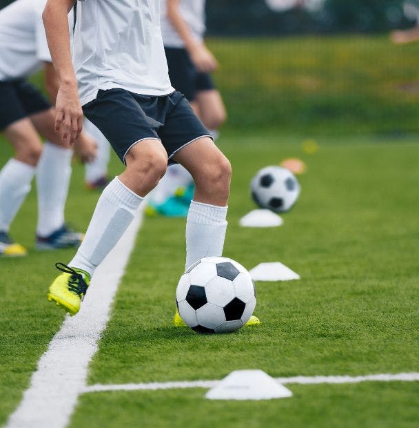 Custom Soccer socks shown on a soccer player kicking a ball during soccer practice