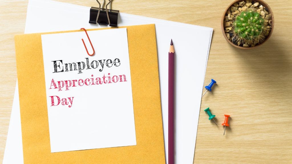 A notebook on a desk showing a sign that says "Employee Appreciation Day" with a pencil and a cactus