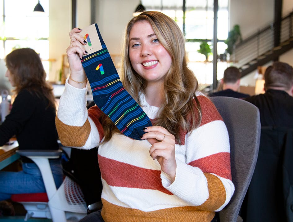Person smiling holding blue custom Google socks