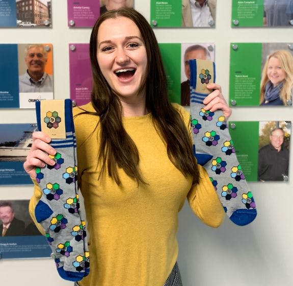 NEXDINE team member holding up a pair of branded socks that she got as an employee appreciation gift